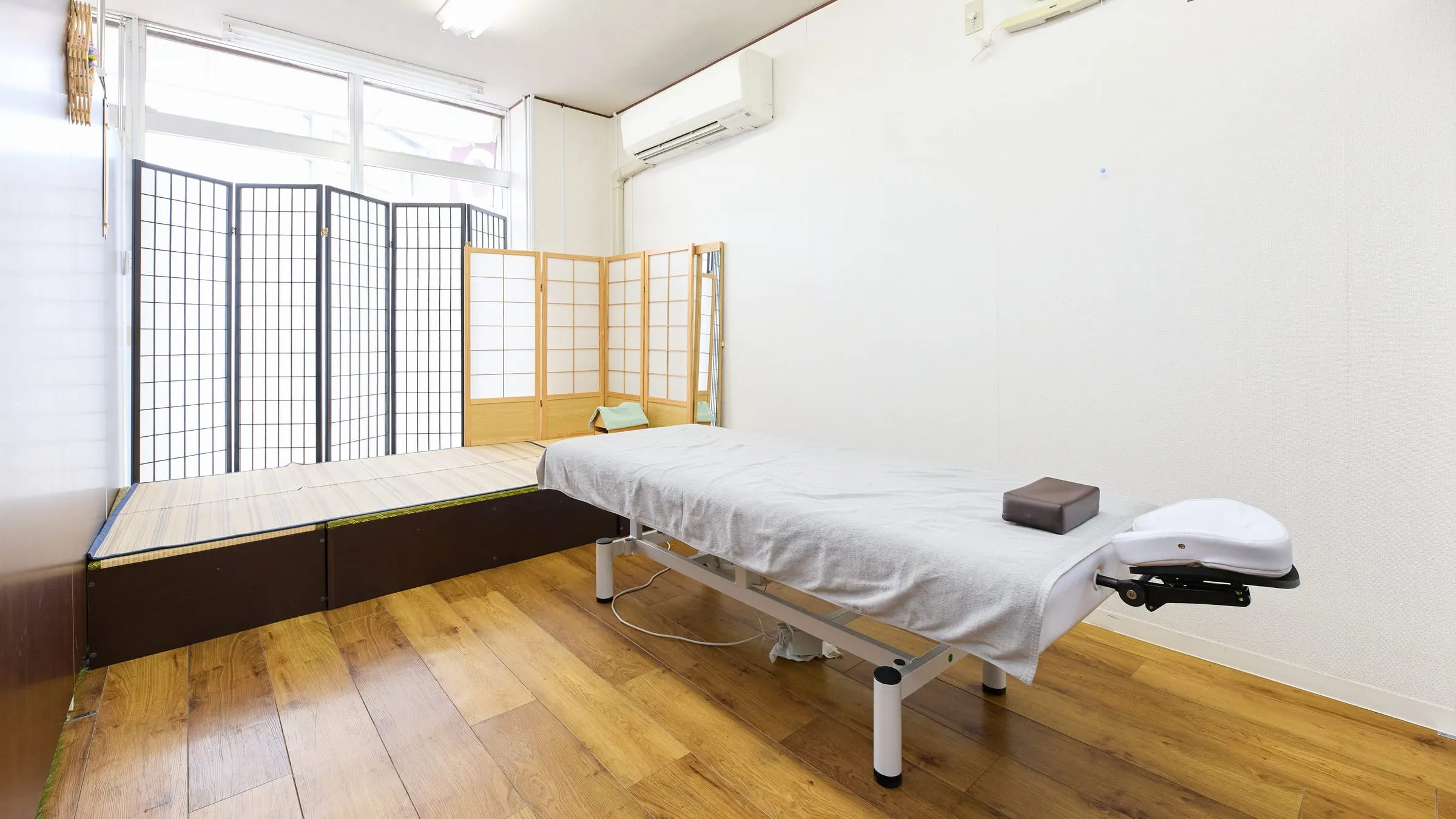 施術室の全景。ベッドが1台置かれ、窓から自然光が入っている。